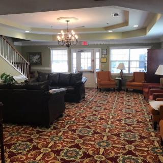 A cozy living room with patterned carpeting, sofas, and a chandelier.