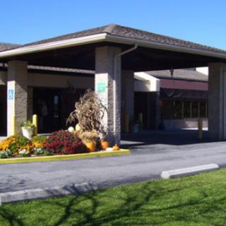 A welcoming entrance to a building with well-maintained landscaping and a covered driveway.