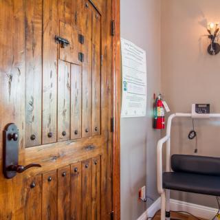 A cozy interior corner featuring a rustic wooden door and a small seating area with a fire extinguisher nearby.