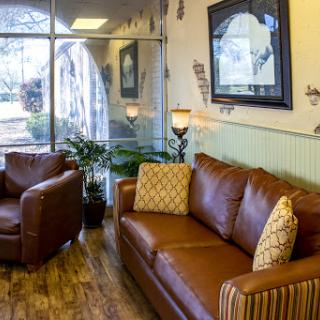 A cozy and modern living room setup featuring a brown leather sofa and armchair, complemented by decorative pillows and indoor plants.