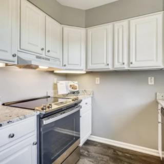 A modern kitchen with white cabinets, a stove, and a microwave.