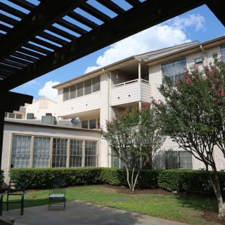 A view of an apartment building with a garden area and blue sky.