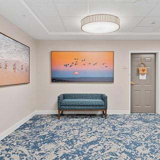 A modern hallway with artwork, a bench, and elegant lighting.