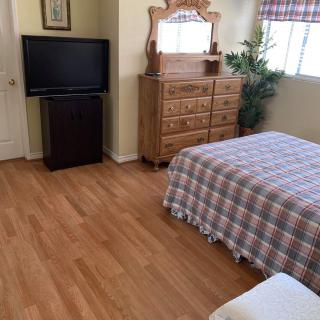 A cozy bedroom with wooden flooring, a dresser, and a television.