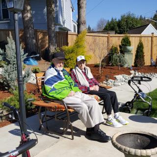 Two people sitting on a bench enjoying a sunny day in the garden.