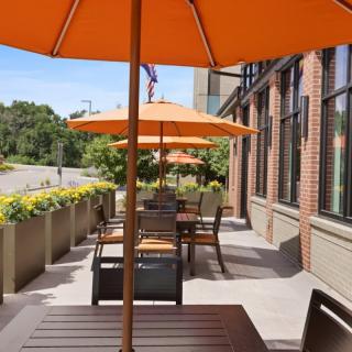 A sunny outdoor patio with orange umbrellas and seating arrangements.