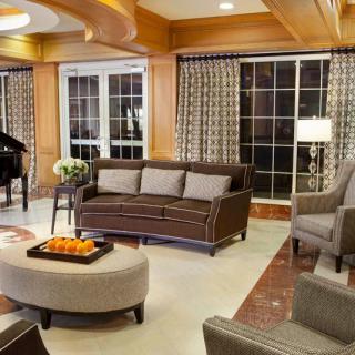 Elegant living room with a modern design, featuring a comfortable sofa, a grand piano, and subtle lighting.
