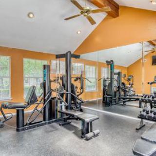A well-equipped gym with various exercise machines and large mirrors.