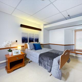 A serene and modern hospital room featuring a comfortable patient bed, bedside table, and soft lighting.