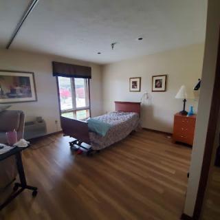 A well-lit hospital room featuring a bed, seating area, and modern furnishings.