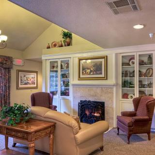 A cozy living room with a fireplace, comfortable seating, and decorated shelves.