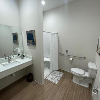 A modern and clean bathroom with a sink, mirror, toilet, and shower area.