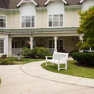 A charming house with a landscaped front yard featuring a white bench and a curved pathway.