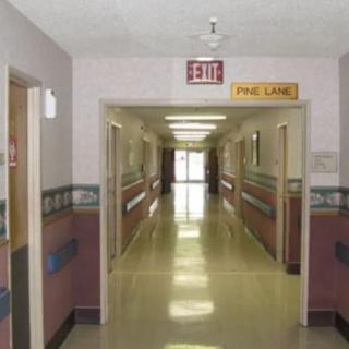 An empty hospital corridor with an exit sign overhead.