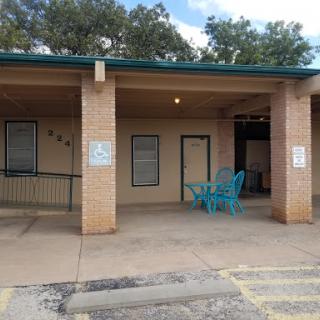 A view of a brick building featuring an accessible entrance and blue outdoor seating.