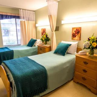 A cozy bedroom with twin beds, decorated with teal accents and floral arrangements.