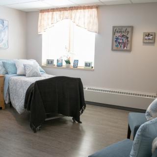 A cozy bedroom with a neatly made bed, soft lighting, and comfortable seating.