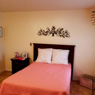 A cozy bedroom with pink bedding and decorative wall art.