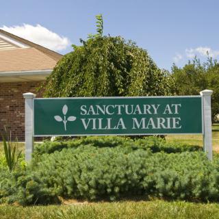 The entrance sign of Sanctuary at Villa Marie surrounded by greenery.