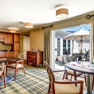 A cozy living space with a kitchenette and dining area, featuring patio doors that open to an outdoor seating area.