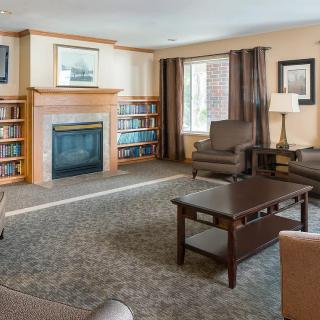 A cozy living room with a fireplace and bookshelves, featuring comfortable furniture and soft lighting.