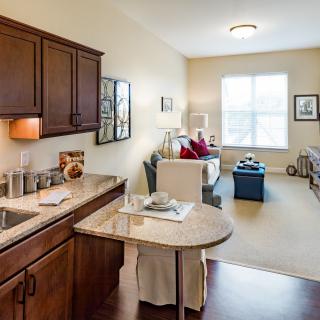 A cozy open-concept kitchen and living room with wooden cabinets and a bright window.