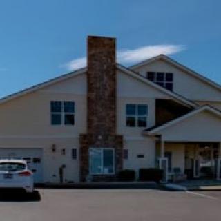 A modern residential building featuring a stone chimney and ample parking.