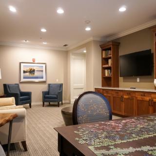 A cozy living room with a seating area, television, and bookshelf.