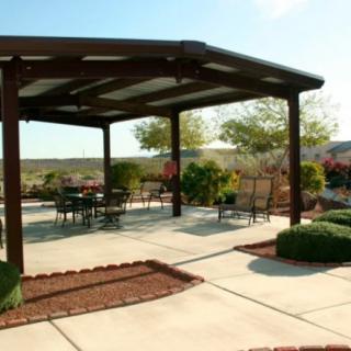 A spacious outdoor patio with a pergola and seating area under a clear blue sky.