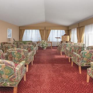 A spacious lounge area with patterned chairs and a red carpet.