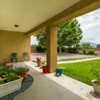A cozy backyard patio with potted plants and comfortable seating overlooking a lush green lawn.
