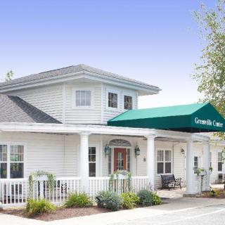A two-story white building with a green awning over the entrance and well-maintained landscaping.