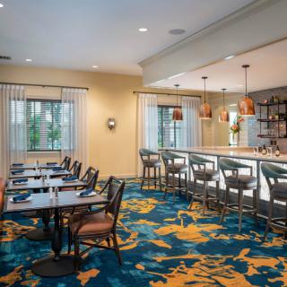 A modern restaurant interior featuring a dining area and bar.