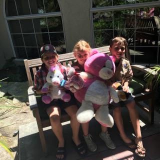 Three friends enjoying a sunny day with their favorite stuffed animals.