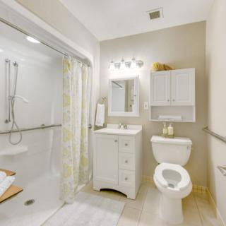 A modern and bright bathroom featuring a shower, toilet, sink, and cabinet.