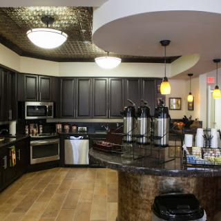 A modern kitchen featuring dark cabinets, a granite countertop, and a well-equipped coffee station.