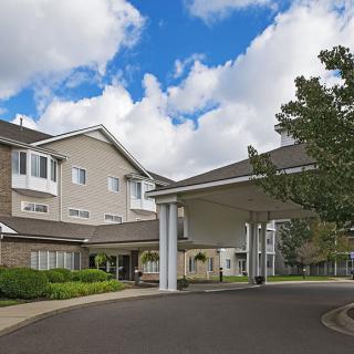 A residential building with a covered entrance under a partly cloudy sky.