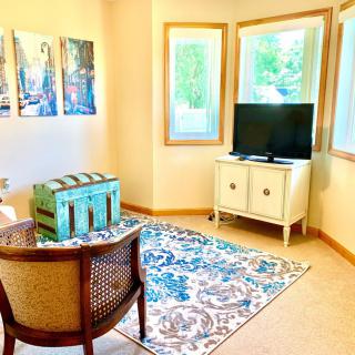 A cozy living room with a TV, artwork on the wall, and a patterned rug.