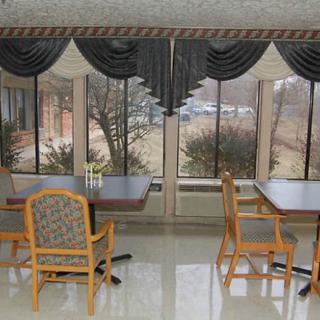 A bright dining area with large windows, tables, and chairs.