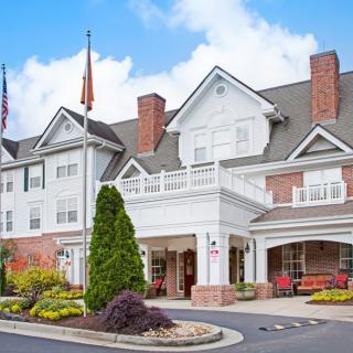 A charming hotel building with a well-landscaped entrance and flags displayed.