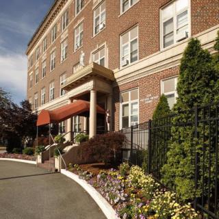 A charming hotel entrance featuring a red awning and beautiful landscaping.