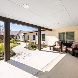 A sunny outdoor patio with comfortable seating and a view of a garden.