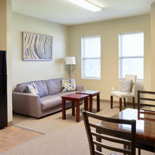 A cozy living room featuring a sofa, table, and natural light from the windows.