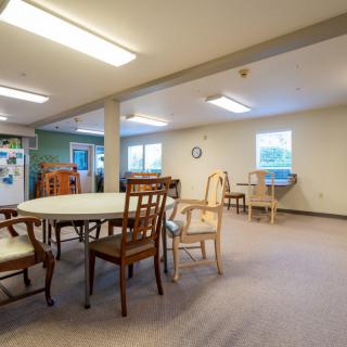 A communal dining area with multiple chairs and tables, illuminated by overhead lighting.