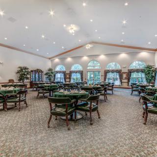 A spacious dining area with multiple tables and chairs, ample lighting, and large windows.