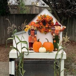 A festive autumn display with pumpkins, scarecrows, and a colorful wreath.