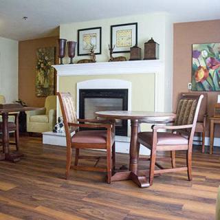 A cozy indoor seating area with wooden chairs and tables, featuring a fireplace and decorative artwork on the walls.