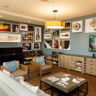 A modern living room with a cozy atmosphere, featuring an art gallery wall and a grand piano.