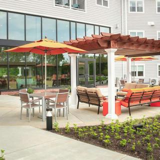 A modern outdoor patio area with seating, pergolas, and umbrellas at a residential or commercial building.