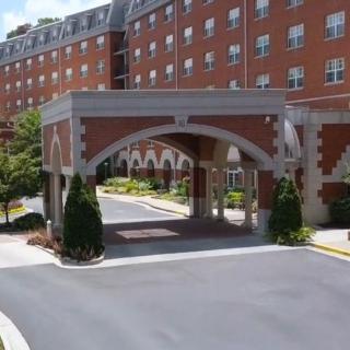 A brick building with an arched entrance and landscaped driveway.